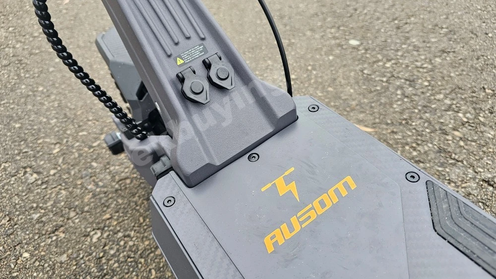 Side view of the scooter deck showing two open charging ports with dust covers on the Ausom DT2 Pro.