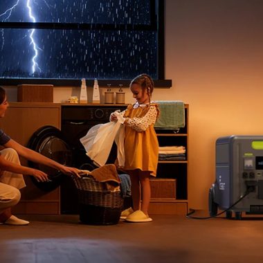 Portable power station powering a lamp and washing machine in a cozy living room during a European winter storm blackout.