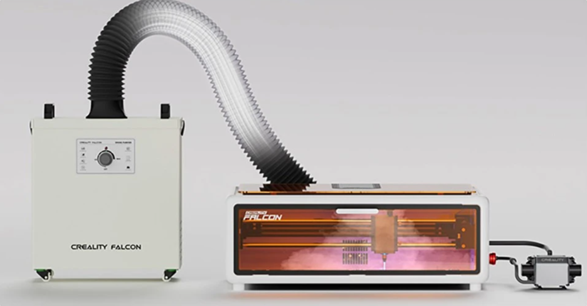 A complete, safe indoor laser engraving setup showing a rigid enclosure on a desk connected via a large hose to a portable fume extractor filtration unit on the floor.